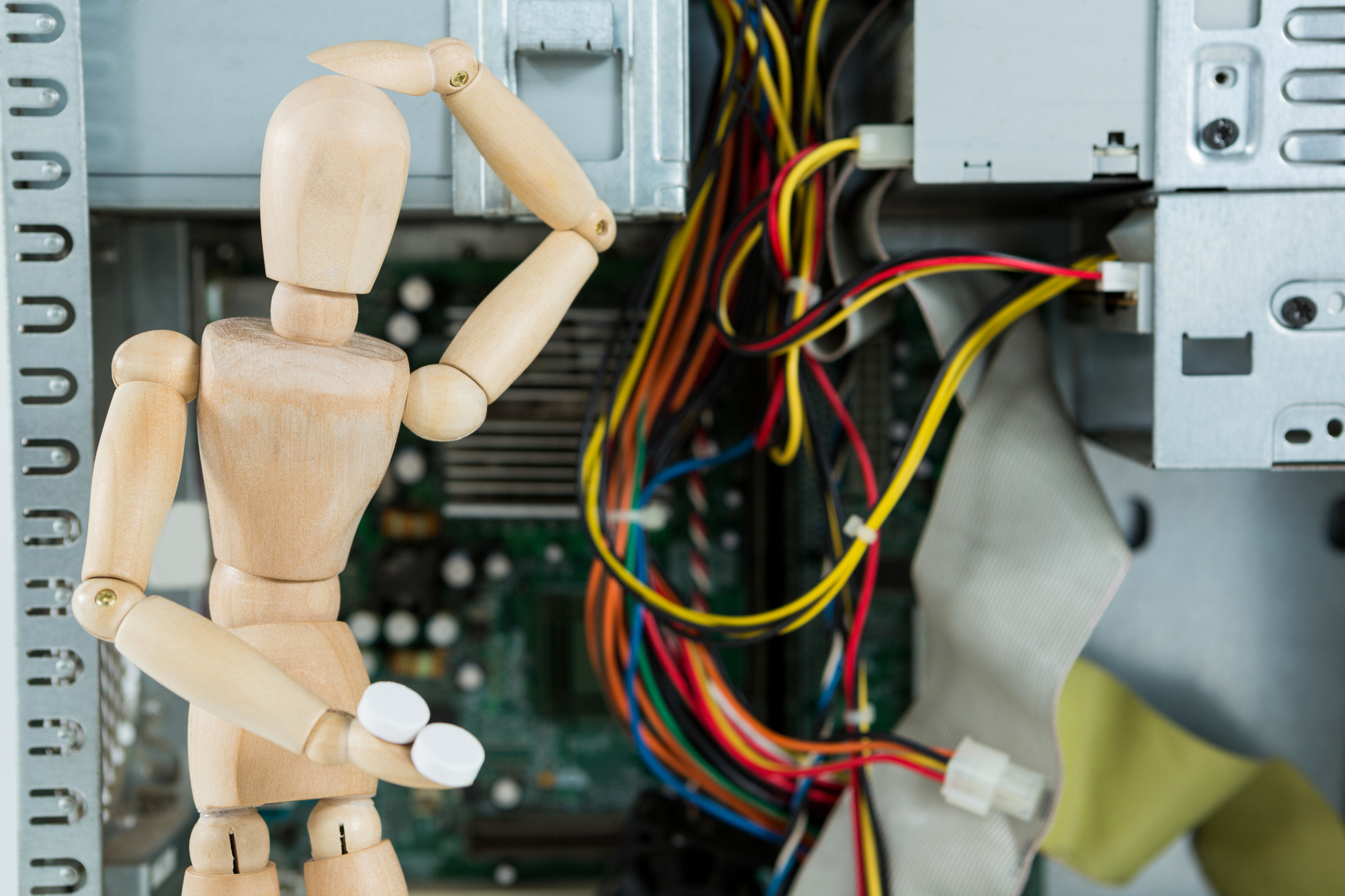 玩具人体模型在 IT 电线前摆出挠头的姿势。